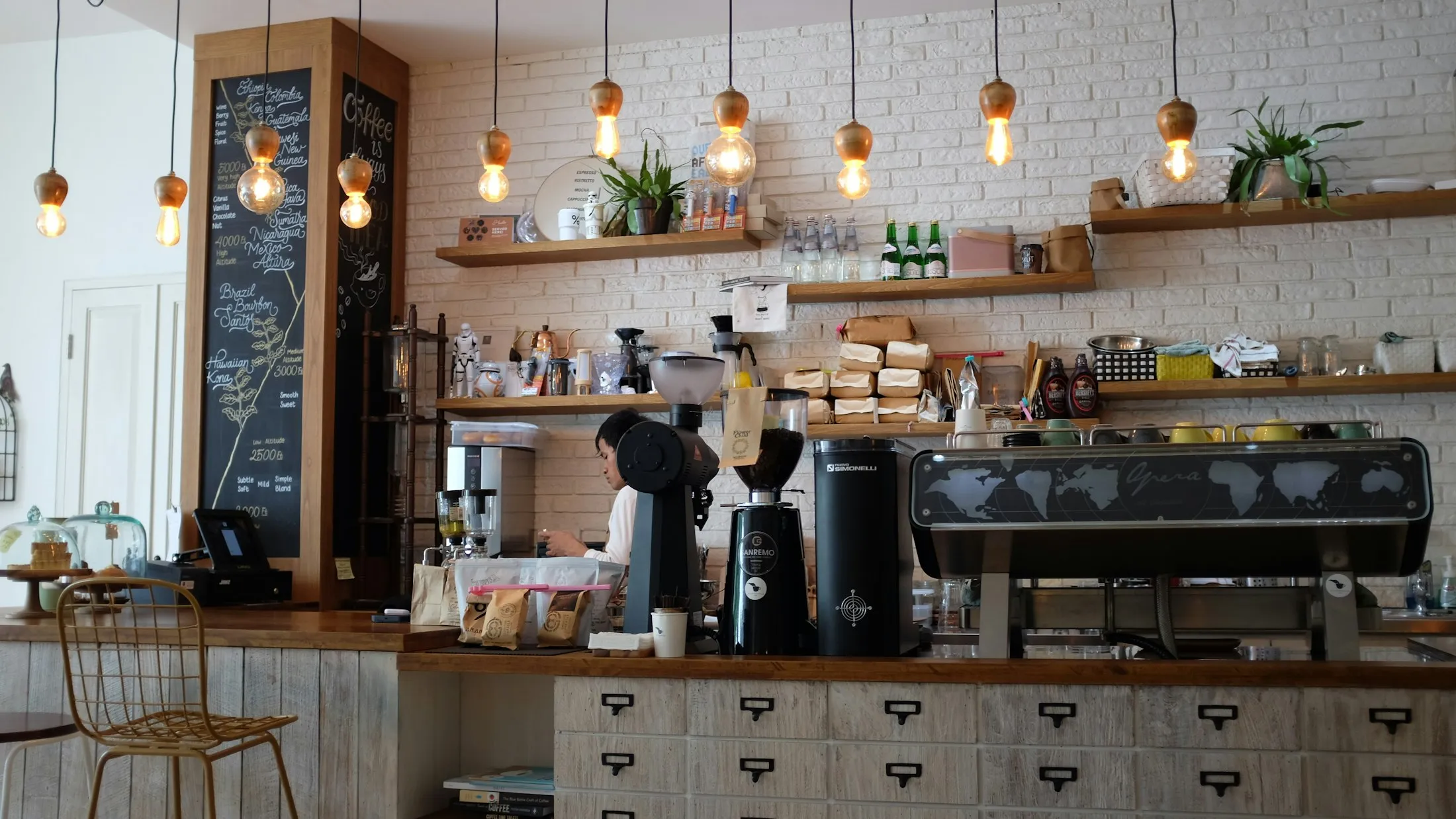 The espresso counter with hanging Edison bulbs and small potted plants on shelves